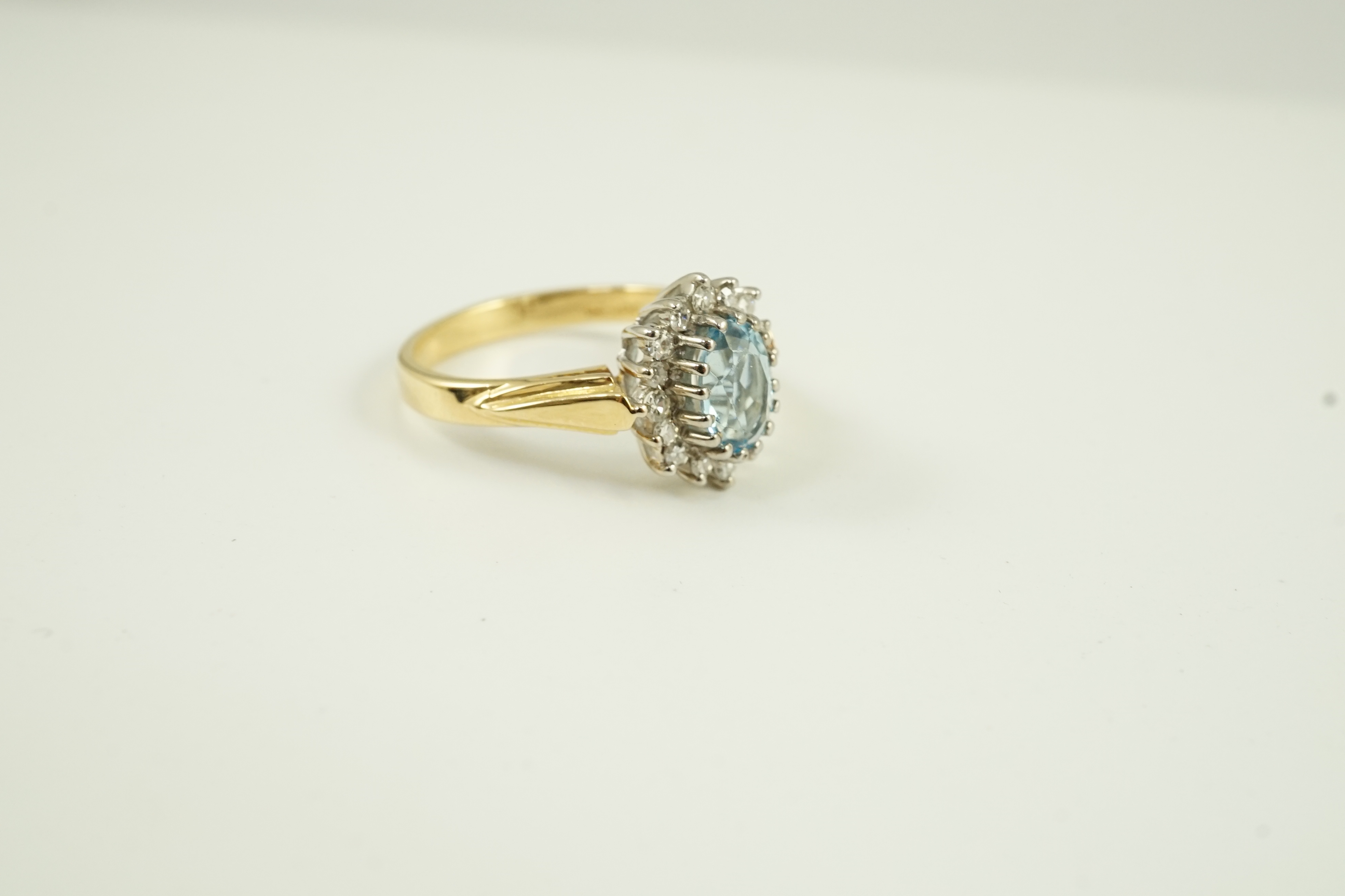 A modern 18ct gold aquamarine and diamond set oval cluster ring, size K/L, gross weight 3.8 grams.